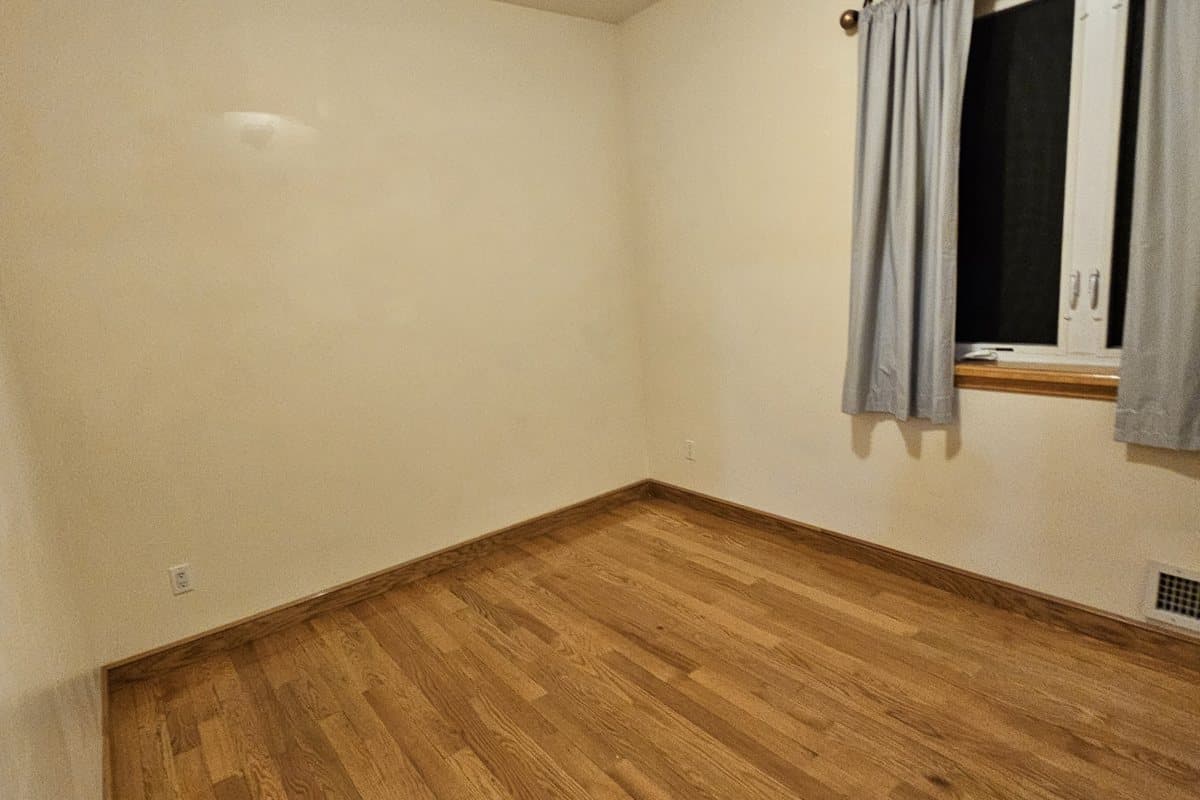Bright empty room with spotless hardwood floors after a move-out clean